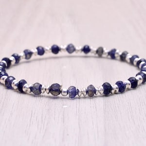 Può includere: Un braccialetto delicato realizzato con perline d'argento alternate a piccole perline di pietre preziose blu scuro.