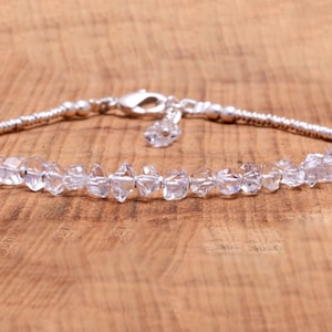 Könnte beinhalten: Ein silbernes Armband mit einer zarten Kette und klaren Quarzkristallen. Die Kristalle sind facettiert und haben einen funkelnden Look.