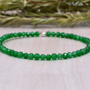 Pode incluir: Um bracelete de jade verde com fecho de prata. O bracelete é feito de pequenas contas facetadas.