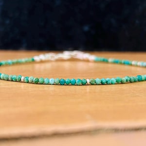May include: A delicate turquoise gemstone necklace with silver beads. The necklace is made of small, round beads and is strung on a silver chain.