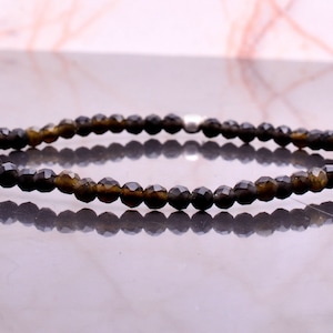 Könnte beinhalten: Ein Armband aus schwarzen Edelsteinperlen mit einem silbernen Verschluss. Die Perlen sind facettiert und haben einen dezenten Schimmer.