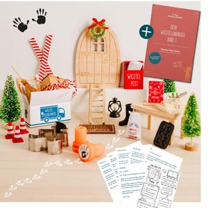 Könnte beinhalten: Eine Miniatur-Holztür mit Kranz, ein roter Briefkasten mit der Aufschrift "Wichtel Post" und ein Buch mit dem Titel "Dein Wichtelhandbuch Band 1". Die Szene umfasst kleine Bäume, eine Leiter und eine Box mit dem Text "Wichtel Umzugexpress".