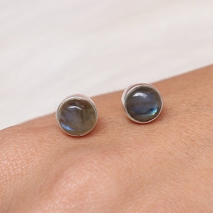Puede incluir: Un par de pendientes de botón de plata con piedras redondas de labradorita iridiscente.