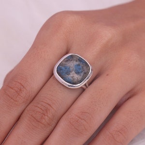 May include: A silver ring featuring a square blue and grey gemstone.
