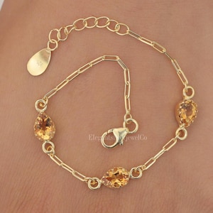 May include: A gold-toned chain bracelet featuring three pear-shaped, faceted yellow gemstones spaced evenly along the links. The bracelet includes a lobster claw clasp and an extender chain with a small teardrop-shaped tag stamped with 925.