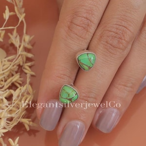 Op de afbeelding: Een paar zilveren oorbellen met groene turquoise stenen. De oorbellen hebben de vorm van een driehoek.