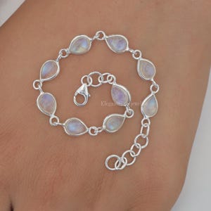 May include: A silver bracelet with teardrop-shaped moonstone beads. The bracelet has a lobster clasp closure and a silver chain extender.