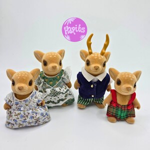 May include: Four miniature deer figurines with brown fur and spotted patterns. They are dressed in various outfits, including dresses and a vest with pants. One deer has antlers. The image includes a purple circle with the text "Hapits".