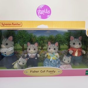May include: A box of Sylvanian Families Fisher Cat Family toys. The box shows a family of five gray and white cats with black stripes. The cats are wearing different outfits. The box is pink and white with the words "Fisher Cat Family" and "5812" on it.