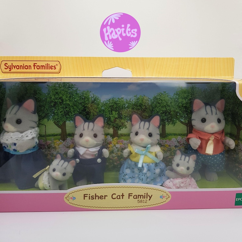 May include: A box of Sylvanian Families Fisher Cat Family toys. The box shows a family of five gray and white cats with black stripes. The cats are wearing different outfits. The box is pink and white with the words "Fisher Cat Family" and "5812" on it.