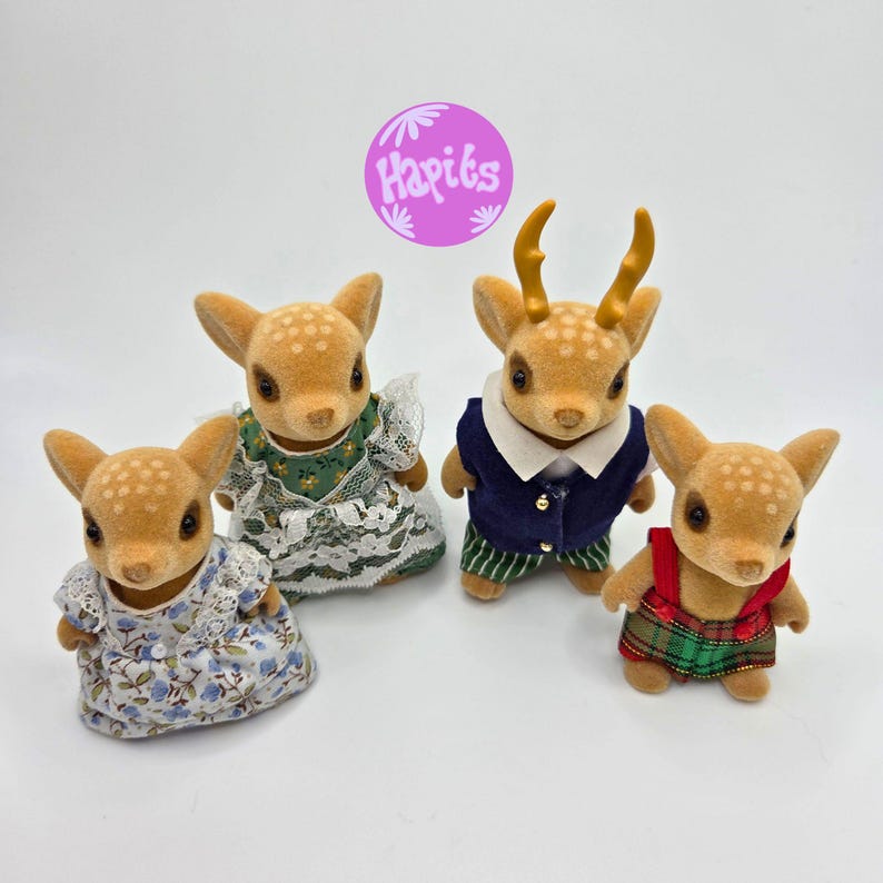 May include: Four fawn figurines with detailed fur and clothing. One fawn wears a blue and white floral dress, another a green dress with lace, a third a navy vest and striped pants, and the last a red and green plaid outfit. The image includes the text "Hapits".