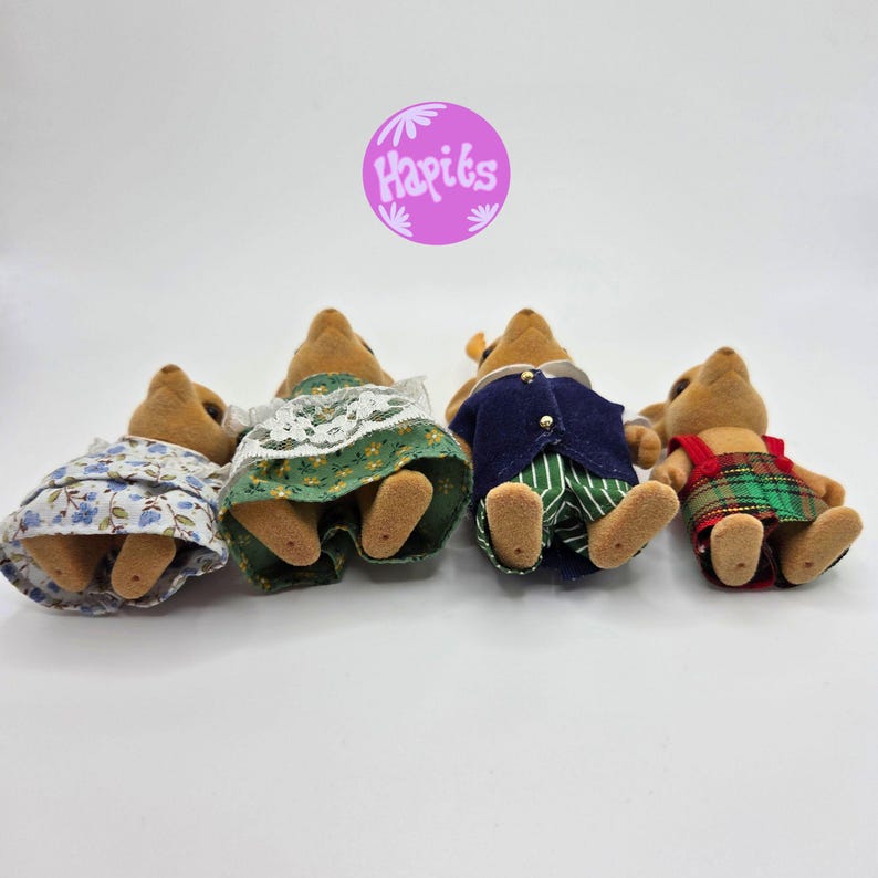 May include: Four miniature toy animal figures, each wearing different outfits. One wears a blue floral dress, another a green dress with white lace, a third a navy blue jacket and green striped pants, and the last a red and green plaid dress.