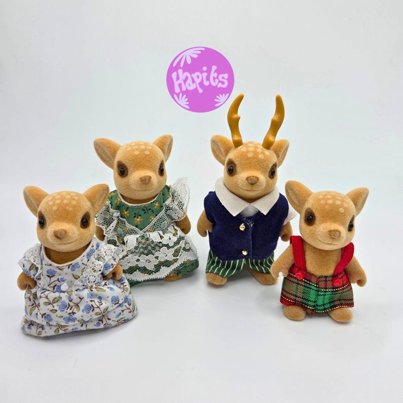 May include: Four fawn-colored deer figurines, each with a unique outfit. One wears a floral dress, another a green dress with lace, a third a navy vest and striped pants, and the last a plaid overall. A purple circle with the text "Hapits" is in the background.