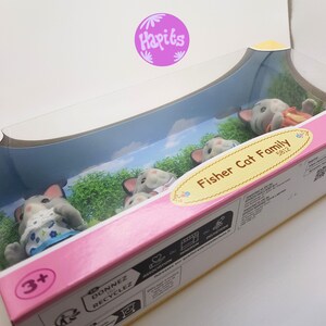 May include: A box of Fisher Cat Family figurines. The box is pink and white with a picture of the four gray cats on the front. The box says "Fisher Cat Family 5812" on the front. The box is for ages 3 and up.