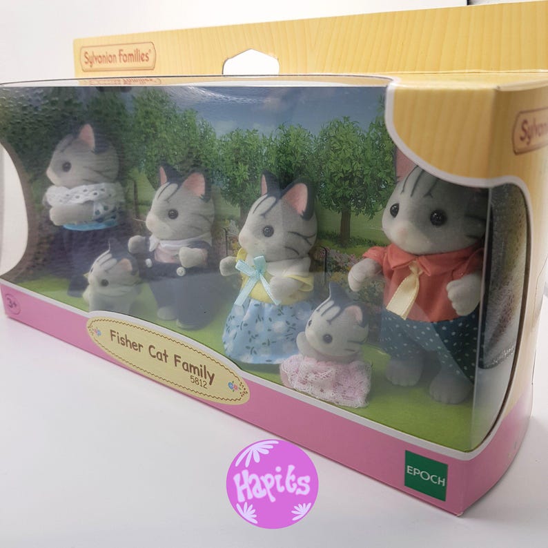 May include: A box of Sylvanian Families Fisher Cat Family toys. The box shows five gray and white cats with black stripes. The family includes a father, mother, two children, and a baby. The box is pink and white with the words "Fisher Cat Family 5812" on the front.
