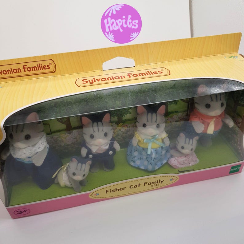 May include: A Sylvanian Families Fisher Cat Family toy set in a clear plastic box. The set includes five figures: a father, mother, son, daughter, and a baby. The figures are all gray and white with black stripes. The box is pink and white with the words "Sylvanian Families" and "Fisher Cat Family" printed on it.