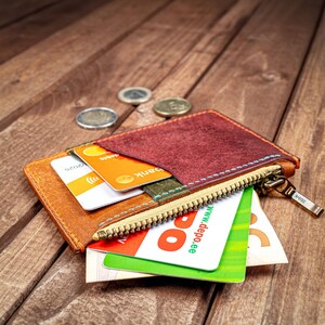 May include: A brown leather wallet with a zipper closure and multiple card slots. The wallet is open and contains several cards, including a credit card with the text "www.depo.ee".