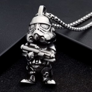 Könnte beinhalten: Eine silberfarbene Halskette mit einem detaillierten, dreidimensionalen Anhänger eines Stormtroopers aus Star Wars. Der Anhänger hält ein Blastergewehr.