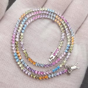 May include: A silver necklace with a rainbow of colorful gemstones. The necklace is composed of multiple strands of small, round gemstones in shades of pink, purple, blue, yellow, and orange. The clasp is silver.