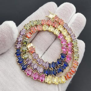 Puede incluir: Un collar de cadena de oro con piedras preciosas ovaladas en un arcoíris de colores. La cadena es de oro y las piedras preciosas están engastadas en un engaste de garras.