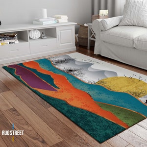 May include: Abstract area rug with a colorful landscape design featuring a deer, trees, and a sun. The rug has shades of teal, orange, purple, and gold.