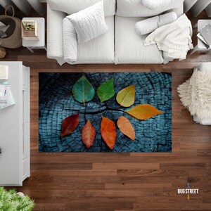 May include: A blue and brown rug with a wood grain pattern and a circle of colorful leaves in the center.