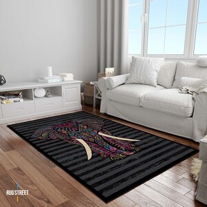 May include: A black and white striped rug with a colorful elephant design. The elephant has pink, blue, green, and yellow details. The rug is on a wooden floor in a living room setting.