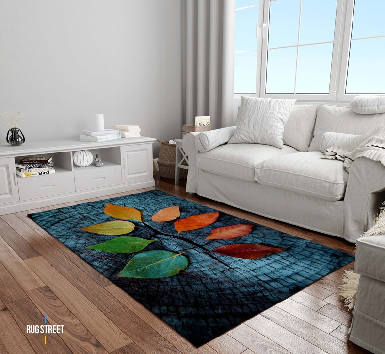 May include: A blue and brown rug with a wood grain pattern and colorful leaves. The leaves are in shades of red, orange, yellow, green, and blue.