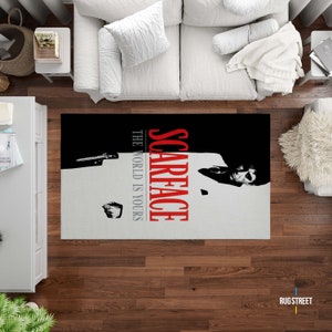 May include: A black and white rug with a red and white "Scarface" logo and the text "The World Is Yours". The rug features a black and white image of a man in a suit.