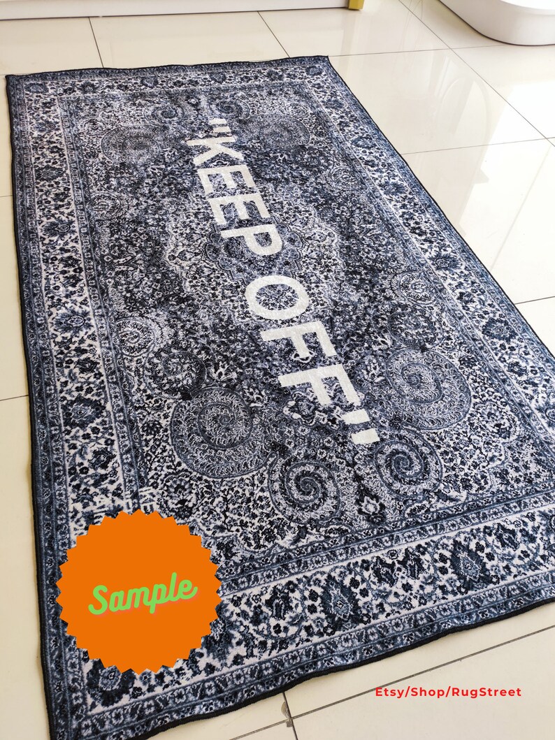 May include: A black and white patterned rug with the text "KEEP OFF!" in white lettering. The rug has a sample label in the lower left corner.