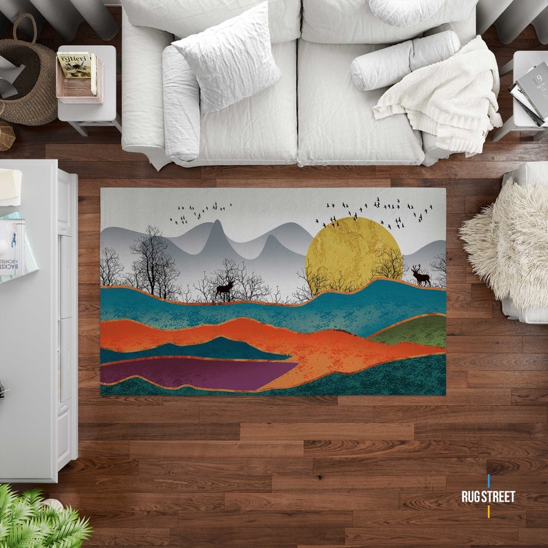 May include: A colorful abstract rug with a mountain landscape, a large yellow sun, and two deer. The rug has a teal, orange, purple, and green color scheme.