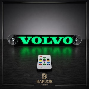 Op de afbeelding: Een zwarte LED-lichtbalk met het woord "VOLVO" in heldergroene letters. Inclusief een afstandsbediening met meerdere gekleurde knoppen. De lichtbalk is bevestigd met zuignappen. De merknaam "BARJOE PRINT" staat onderaan.