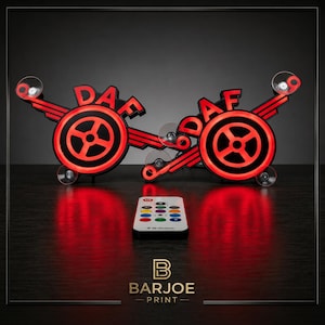 Peut inclure: Deux enseignes lumineuses LED avec le logo DAF rouge et noir, accompagnées d'une télécommande. Les enseignes présentent un design circulaire avec le logo DAF et sont fixées avec des ventouses. La télécommande propose plusieurs options de couleurs.