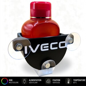 Può includere: Una bottiglia rossa con tappo rosso e finiture dorate è inserita in un supporto nero con la scritta "IVECO" in bianco. Il supporto ha tre ventose trasparenti e una base bianca. La parte inferiore dell'immagine presenta testo e icone per RGB, USB, ventosa e temperatura.
