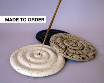 May include: White, brown, and black ceramic incense holders with a spiral design. The holders are made to order. An incense stick is placed in the white holder.