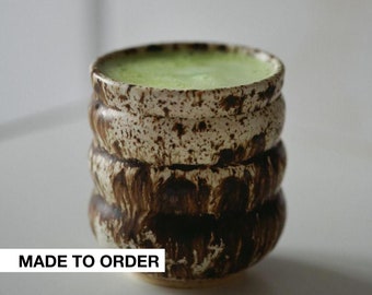 Puede incluir: Una taza de cerámica marrón y blanca con un líquido verde en su interior. La taza tiene un diseño texturizado y en capas. El texto "MADE TO ORDER" es visible en la parte inferior de la imagen.