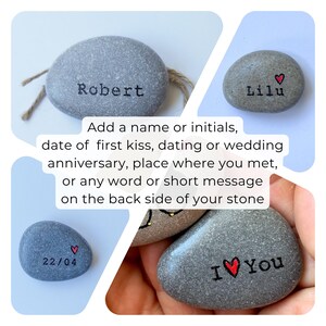 May include: A collection of personalized gray stones with text and heart symbols. One stone reads "Robert", another "Lilu", and a third displays "22/04". A fourth stone says "I ❤️ You". The image also includes text about customization.