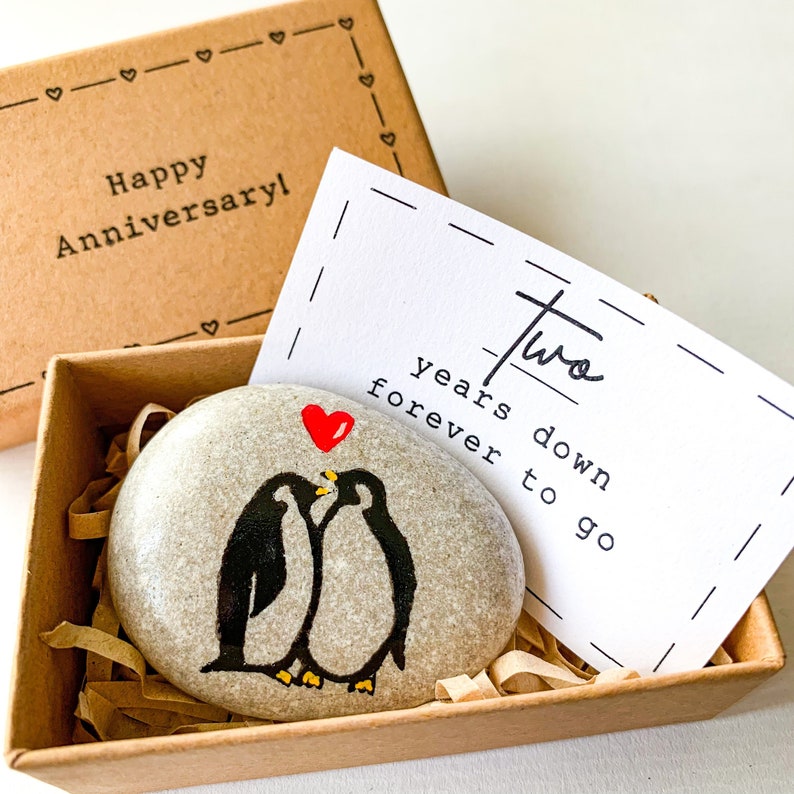 Hand painted on a pebble penguin couple - little 2nd anniversary gift for him and her for celebration 2 year marriage of husband and wife. Two years down, forever to go greeting card. Small gift box with Happy 2 anniversary sign