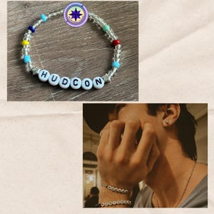 May include: A beaded bracelet with the word "HUDCON" spelled out in white letter beads. The bracelet features clear beads, star-shaped beads, and colorful accent beads in blue, yellow, red, and green. A logo is visible in the top left corner.
