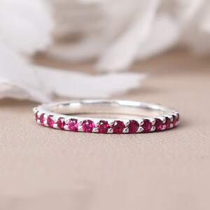 May include: A silver band ring with a row of small, red gemstones.