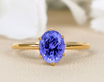 Puede incluir: Un anillo de oro con una gran piedra preciosa azul de forma ovalada engastada en garras.