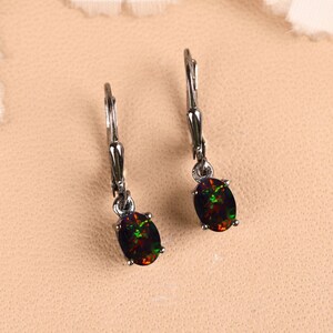 Peut inclure: Une paire de boucles d'oreilles pendantes avec des pierres précieuses ovales et sombres. Les pierres présentent un mélange de couleurs vertes, rouges et noires. Les boucles ont un sertissage en métal argenté et un fermoir à levier.