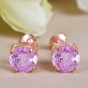 Puede incluir: Un par de pendientes de botón de oro rosa con piedras redondas de color rosa claro.