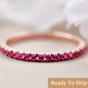 Könnte beinhalten: Ein zarter Roségold-Bandring mit einer Reihe kleiner rosafarbener Edelsteine.