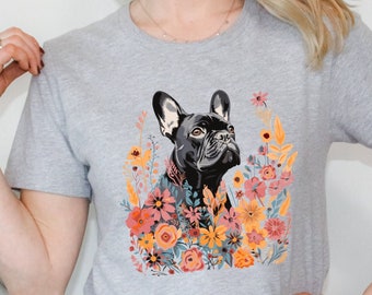 May include: A grey t-shirt featuring a black French bulldog surrounded by colourful flowers. The dog is looking upwards and the flowers are in shades of pink, orange and yellow.