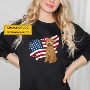 May include: A black sweatshirt with a graphic of a golden doodle dog standing in front of an American flag. The text "CHOICE OF DOG" and "DIFFERENT DOG BREEDS" is printed on a yellow banner at the top of the image.