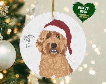 May include: A round, white ceramic Christmas ornament with a brown and white dog wearing a red Santa hat. The dog's name, "Teddy", is written in cursive on the ornament.