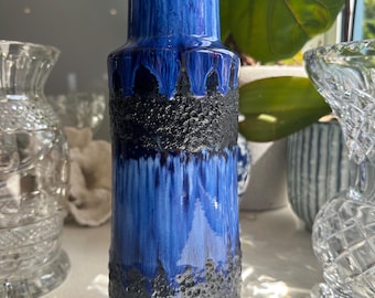 May include: A blue and black ceramic vase with a textured design. The vase has a wide base and a narrow neck.