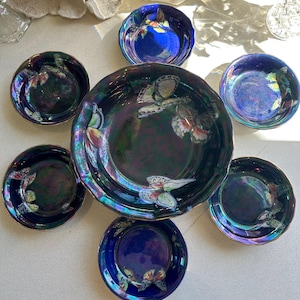 May include: Set of seven iridescent blue and green ceramic bowls with gold trim and butterfly designs. The bowls are arranged in a circle with the largest bowl in the center.