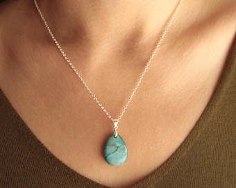 May include: A silver chain necklace with a teardrop-shaped pendant. The pendant is a marbled turquoise color with darker blue-green veining. The necklace is displayed against a neutral background.